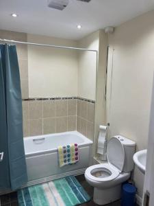 a bathroom with a tub and a toilet and a sink at Promenade Sea View Apartment in Ballycastle