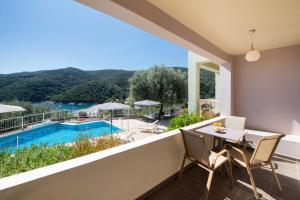 a balcony with a table and chairs and a swimming pool at Rouda Village in Mikros Gialos