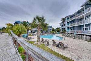 a swimming pool with chairs and a wooden fence at Breezy Tybee Island Condo - 100 Yards from Beach! in Tybee Island