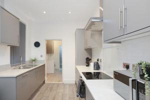 a kitchen with white cabinets and white counter tops at Leicester Serviced Accomodation with Free Sky and BT Sports in Leicester