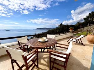 a patio with a table and chairs and the ocean at Grand Blue Terrace - Island house by Hostandros in Batsi