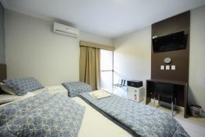 a hotel room with a bed and a television at Universitario Hotel in Itapetininga