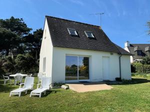 une maison blanche avec des chaises blanches et une table dans l'établissement Résidence D22-ile Grande - Maison de pêcheur dans un jardin sur la mer MAE-3464, à Pleumeur-Bodou
