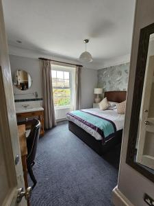um quarto com uma cama, uma secretária e uma janela em Cockhaven Arms em Bishopsteignton