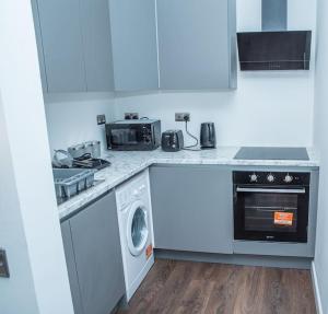 uma cozinha branca com um fogão e uma máquina de lavar louça em Aylesbury Apartment 1 with free parking em Buckinghamshire