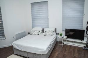 a white bedroom with a bed and a television at Aylesbury Studio-1 with free parking in Buckinghamshire