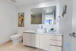 a bathroom with a sink and a toilet and a mirror at Infinite View Balcony - Amazing Pool - Gym in Hallandale Beach