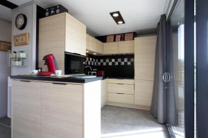 una cucina con armadi in legno e un apparecchio rosso di Le Chalet Cetri - Welkeys a Saubrigues
