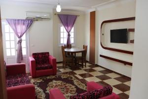ein Wohnzimmer mit Stühlen, einem Tisch und einem TV in der Unterkunft Sandy House in Madinat as-Sadis min Uktubar