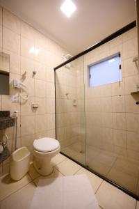 a bathroom with a toilet and a glass shower at Universitario Hotel in Itapetininga