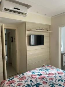 een slaapkamer met een bed en een tv aan de muur bij Apartamento Edificio Sunset 1404 in Vila Velha