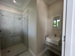 La salle de bains est pourvue d'une douche et d'un lavabo. dans l'établissement Elegant Guest House Sandton, à Johannesbourg