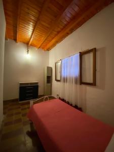 1 dormitorio con cama roja y TV en Néctar en Tinogasta
