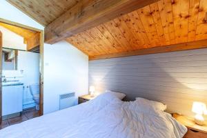 1 dormitorio con cama blanca y techo de madera en Résidence LES ALPAGES - Chalet CHALET ALPAGES 19 pour 10 Personnes 08, en Plagne Villages