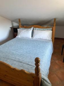 una camera con letto in legno e cuscini bianchi di Moretti Mountain House - Relax in Nature a Gorreta