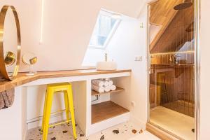 une salle de bain avec un lavabo, un miroir et un tabouret jaune dans l'établissement Le Milkshake - Hypercentre, Cinéma, King size, à Troyes