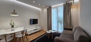 ein Wohnzimmer mit einem Sofa und einem Tisch sowie ein Esszimmer in der Unterkunft TAM Serviced Apartment City Center No3 in Tirana