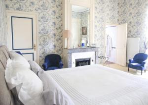 a bedroom with a white bed and a fireplace at Château senailhac in Tresses