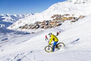 a man riding a bike down a snow covered mountain at Résidence Arcelle - VAL THORENS location: studio cabine en plein centre de la station MAE-9104 in Val Thorens