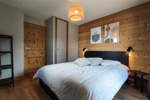 a bedroom with a large white bed with wooden walls at CHALET LUMI - Chalet CHALET MAGDALENA pour 6 Personnes 624 in Valmorel