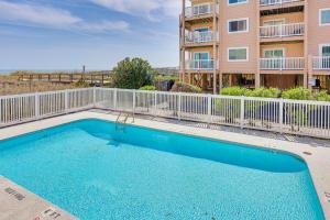 a swimming pool in front of a apartment building at Carolina Beach Condo with Balcony and Ocean Access! in Carolina Beach