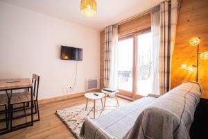 a living room with a couch and a table and a window at Résidence LUMI BATIMENT B - Appartement LUMI B pour 4 Personnes 994 in Valmorel