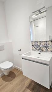 Baño blanco con aseo y lavamanos en Appartement Le Porto en Cholet
