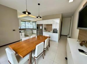 cocina con mesa de madera y sillas blancas en casa en samborondon, en Guayaquil