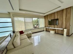 casa en samborondon في غواياكيل: غرفة معيشة كبيرة مع أريكة وتلفزيون