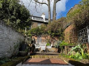 a patio with two chairs and a brick wall at Comfy child/dog friendly garden flat heart Camden in London