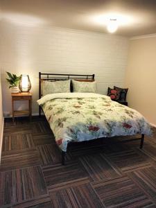 a bedroom with a bed with a floral comforter at Koloona in Wollongong