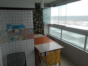 uma cozinha com mesa e cadeiras e uma janela em Apartamento frente mar pé na areia na Praia Grande