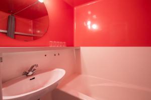 łazienka z czerwonymi ścianami, umywalką i lustrem w obiekcie Résidence Bequi-rouge - Appartement 2 pièces 5 personnes, proche des pistes, au cœur de la station d’Arc 1800 dans le village des Villards MAE-1920 w mieście Arc 1800