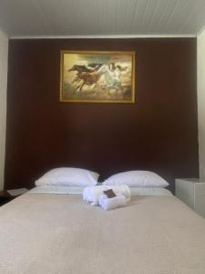 1 dormitorio con 1 cama con una pintura en la pared en Pousada da Heloisa, en Imbituba