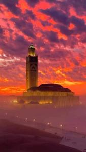 un grand bâtiment avec une tour d'horloge et un coucher de soleil dans l'établissement Magnifique appartement pleine vue mer Marina Casablanca, à Casablanca