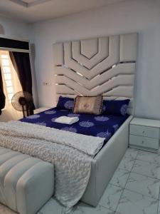a bedroom with a king sized bed with blue sheets at Pentagon Court Phase 1 Apartment Ikota in Lagos