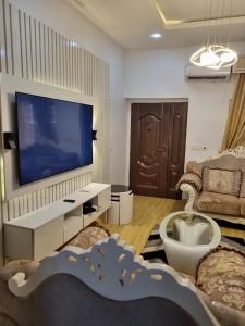 sala de estar con TV de pantalla plana grande en Pentagon Court Phase 1 Apartment Ikota, en Lagos