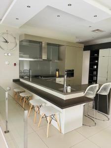a kitchen with a large black counter and chairs at Lulanipho Abode in Hartbeespoort