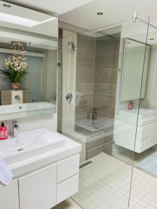 W łazience znajduje się biała umywalka i prysznic. w obiekcie Lulanipho Abode w mieście Hartbeespoort