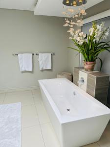 a white bathroom with a sink and a vase of flowers at Lulanipho Abode in Hartbeespoort