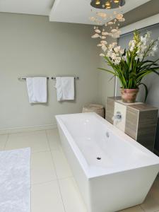 a white bathroom with a sink and a vase of flowers at Lulanipho Abode in Hartbeespoort +21 photos