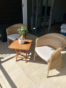 two wicker chairs and a coffee table on a patio at Modern, beautiful 1 bed with views -V&A Waterfront in Cape Town