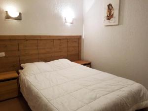 een slaapkamer met een wit bed met 2 verlichting aan de muur bij Résidence Roc Belleface C - 3 Pièces pour 8 Personnes 98 in Arc 1600