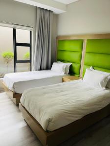 two beds in a room with a green headboard at Lulanipho Abode in Hartbeespoort
