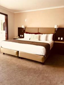 - une chambre avec un grand lit et des oreillers blancs dans l'établissement Hotel Guadalajara Plaza Ejecutivo, à Guadalajara