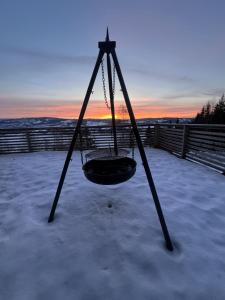 un columpio en la nieve con la puesta de sol en el fondo en All inclusive villa, en Lillehammer