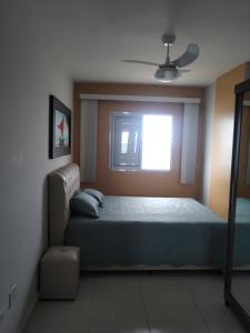 um quarto com uma cama e uma janela em Apartamento frente mar pé na areia na Praia Grande