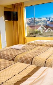 two beds in a room with a window at Hotel Independencia in Huaraz