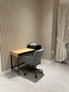 einen Schreibtisch und einen Stuhl in einem Zimmer mit einem Vorhang in der Unterkunft Dutch Luxury Apartment - Private Beach in Abu Dhabi