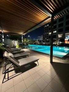 eine Terrasse mit Liegestühlen und einem Pool in der Nacht in der Unterkunft Dutch Luxury Apartment - Private Beach in Abu Dhabi